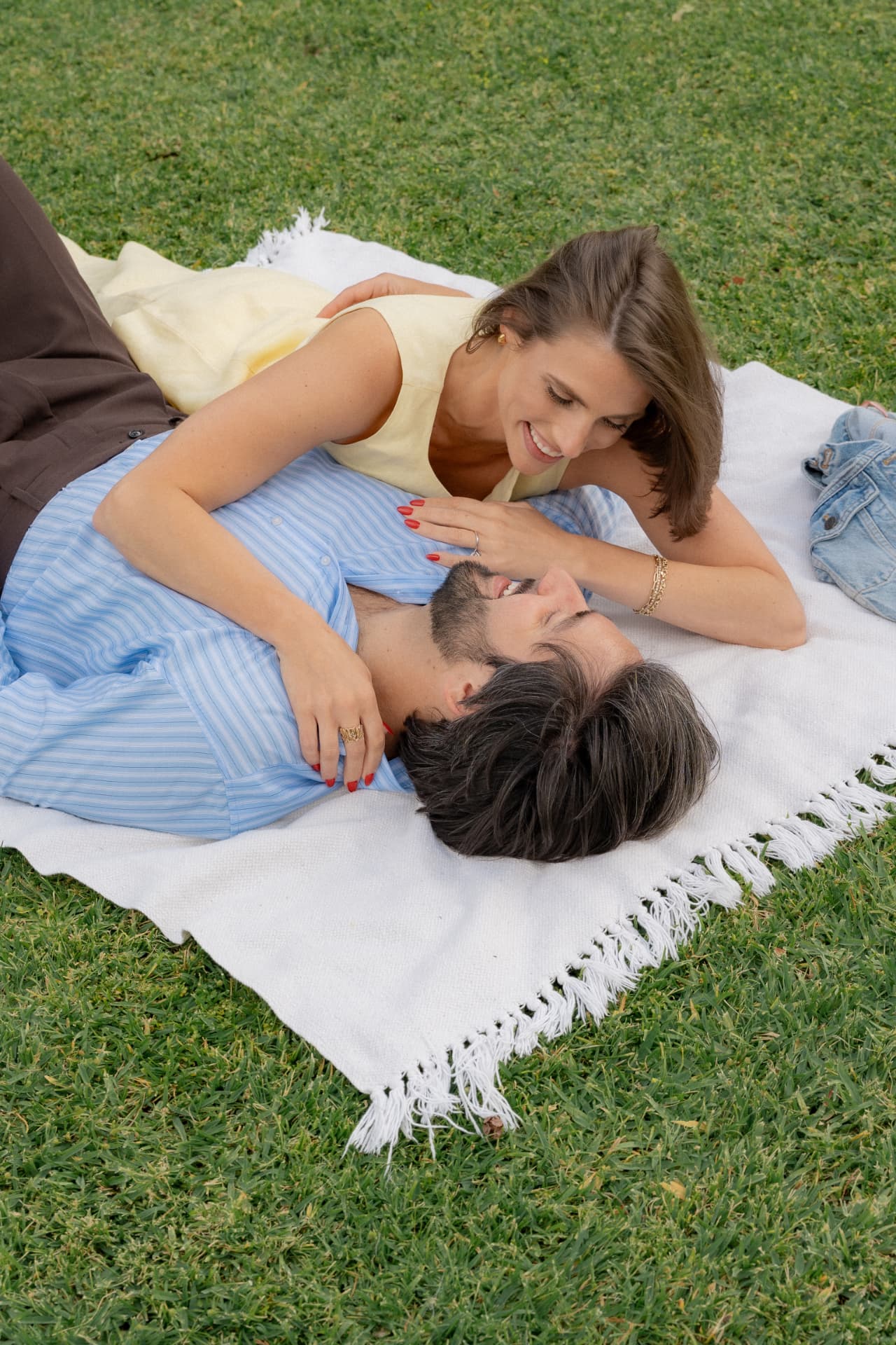 Kayla and Bruno lying on a fringed picnic blanket on the lawn