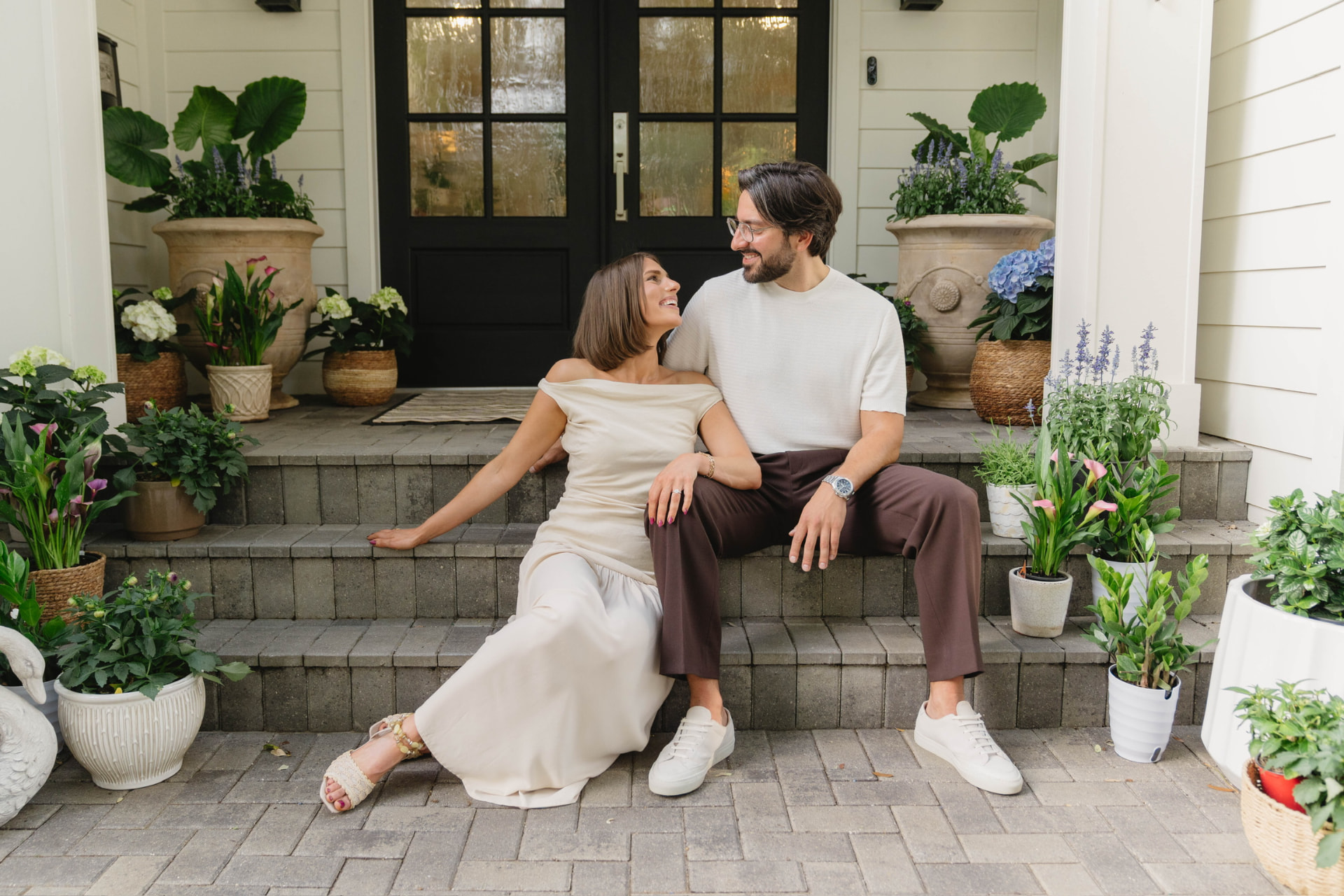 Kayla and Bruno sitting together on front steps surrounded by plants